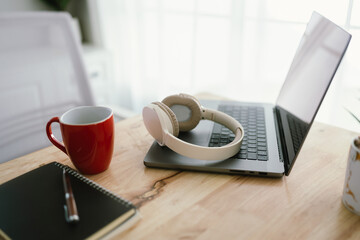 a modern, minimalist desk workspace with a laptop, headphones, notepad, cup of coffee, and houseplan