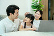 © STOCK88PHOTOGRAPHER - A tender parenting moment. The father affectionately strokes his daughter's hair as they interact in front of a laptop at home.