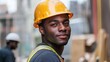© Molly P - A confident male construction worker smiles while wearing a safety helmet and vest. The background suggests an active construction site, showcasing labor and teamwork in a vibrant urban setting.