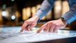 © INT888 - Close up of hands pointing to features on city map during planning or discussion, with blurred background creating professional and focused atmosphere