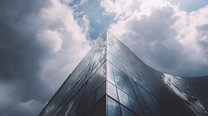 Poster - Low Angle View of Modern Glass Skyscraper Under Cloudy Sky