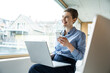 © Westend61 - Businesswoman smiling while using laptop and smartphone in office