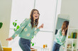 © deagreez - Young cheerful woman wearing a daisy-patterned cardigan enjoys a moment at home in a cozy and stylish living room with casual interior