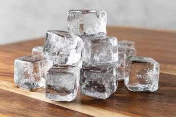 Poster - Clear ice cubes stacked on a wooden surface ready for refreshing drinks and cocktails