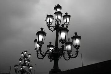 Poster - Dramatic view of street lamps illuminated against a cloudy sky in an urban landscape at dusk