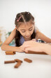 © bongkarn - Asian kid or a little girl in purple shirt is collecting wooden blocks to rebuild a jenga tower.
