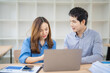 © Tj - Two asian businesspeople are discussing working using laptop computer and digital tablet at modern startup office, businesspeople working together concept