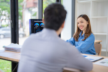 Poster - Two marketing managers are sitting at a desk and discussing consumer demographics using charts displayed on a laptop, working together on a project in a modern office