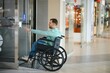 © Serhii - Customer in wheelchair calling the elevator in a modern shopping mall