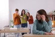 © New Africa - Teenage girl suffering from bullying at school, selective focus