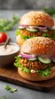 © Natchanok - Close-up of two lentil burgers with fresh vegetables and sauce on a wooden board, studio shot, food photography