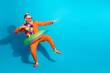 © deagreez - Fun spirited man in orange suit with tropical accessories posing against a vibrant blue background inspiring humor and positivity