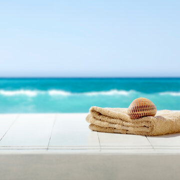 Summer composition on wooden pier on sandy beach with blue sea and sky background. Copy space for product or text.