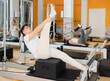 © JackF - Male gym visitor performs exercises to increase flexibility and stretch leg muscles on reformer. Girl performs sequence of tasks, circular workout