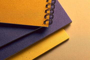 Poster - Colorful spiral notebooks stacked on a textured surface create a vibrant and artistic workspace arrangement