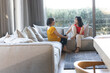 © Wavebreak Media - Asian mother and daughter chatting in living room with gray sofa, pillows, coffee table, dark rug