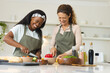© Wavebreak Media - Chopping vegetables, Diverse female friends preparing meal at kitchen island, with cutting boards
