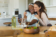 © Wavebreak Media - Laughing Diverse female friends embracing as viewing smartphone at kitchen table, with salad bowl