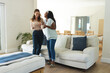 © Wavebreak Media - Laughing Diverse female friends standing in modern living room, with white ceramic coffee mugs