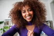 © Studio Marmellata - A young woman with curly hair smiles warmly at the camera. She appears to be on a video call, connecting with someone remotely. Her expression conveys happiness and engagement.