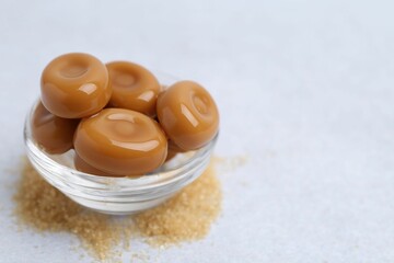 Wall Mural - tasty sweet caramel candies on white table, closeup. space for text