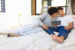 © Wavebreak Media - Relaxing together two men sharing tablet on bed in bright modern bedroom, with pillows and blanket
