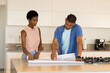 © Wavebreak Media - Examining blueprints, diverse couple planning layout on island countertop in modern kitchen