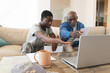 © Wavebreak Media - Examining documents and laptop in living room, African American father and son with military cap