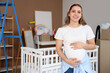© Pixel-Shot - Young pregnant woman near crib in children's room on moving day