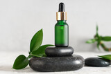 Composition with bottle of essential oil, spa stones and plant leaves on light table