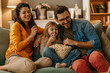 © La Famiglia - Happy family watching tv and eating popcorn on sofa at home