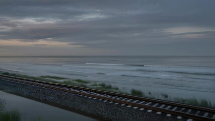 Wall Mural - passenger train traveling along coastal railway during sunrise, revealing scenic ocean landscape wit