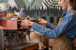 © Rakchanok - Side view, young attractive Asian barista female using professional coffee machine to make hot espresso coffee in cafe, small business start-up for people lifestyle multitask working in coffee shop