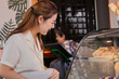 © Rakchanok - Asian young small business owner female service customer ordering using POS cash machine in cafe coffee shop restaurant, barista waitress worker standing in counter bar working in cozy workplace