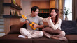© Pichsakul - Asian Couple Enjoying Ukulele Music Together Smiling on Sofa Relaxing at Home Creating a Joyful Atmosphere with Casual Lifestyle Leisure Time and Positive Emotions