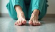 © Pete - Person in scrubs sitting rubbing painful feet indoors. Medical worker suffering from foot discomfort. Healthcare pro experiencing soreness on tile background. Health, medical issues, pain concept.