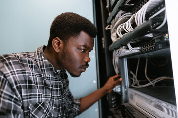 Poster - Technician organizes network cables in server rack during evening hours at tech facility