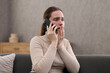 © New Africa - Depressed woman calling hotline for mental health help on sofa at home