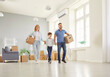 © Studio Romantic - Happy young family with cardboard boxes holding hands and walking around their new house. Cheerful mother, father and son celebrating buying real estate and moving to new apartment. Property purchase.