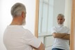 © New Africa - Handsome senior man looking at himself in mirror indoors