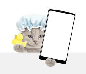 Leinwandbilder - Cute tiny kitten with shower cap on it head holds rubber duck and big smartphone with white blank screen in it paw above blank white banner. isolated on white background