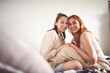 © Louis-Paul Photo - Happy couple cuddling on their bed at home. Romantic young LGBTQ+ couple together in their bedroom. Lesbian couple bonding fondly at home.