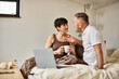 © LIGHTFIELD STUDIOS - A cheerful couple enjoys a warm conversation while sipping drinks in their cozy bedroom