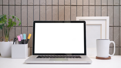 Aufkleber - Creative workspace featuring laptop with blank screen, coffee mug, and potted plant against a modern tile wall.