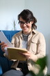 © Andrii Zastrozhnov - Caucasian young female enjoying a book indoors relaxed reading with glasses