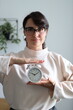 © Andrii Zastrozhnov - Caucasian female adult holding clock in modern indoor setting with plants