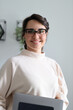 © Andrii Zastrozhnov - Confident young caucasian female wearing glasses with laptop in modern office setting