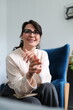 © Andrii Zastrozhnov - Smiling adult caucasian female wearing glasses sitting in modern office