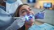 © elimicel - woman receiving teeth whitening treatment from a dentist.The process uses blue light technology for a brighter smile