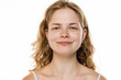 © vladimirfloyd - Portrait of a young woman with wavy blonde hair and freckles, smiling naturally against white background, wearing minimal jewelry and white top